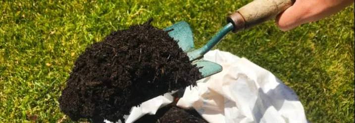 Hand schaufelt Erde aus einem Sack